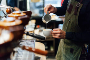 Home barista making coffee in coffee shop, hands holding cup of coffee